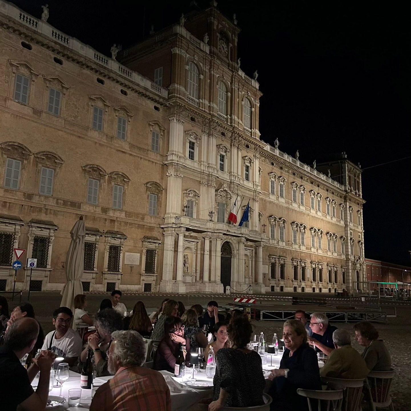 Cena all'aperto in Piazza Roma, davanti al Palazzo Ducale illuminato di sera, Modena.